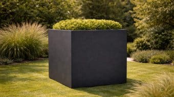 czarna donica w ogrodzie pełnym zieleni