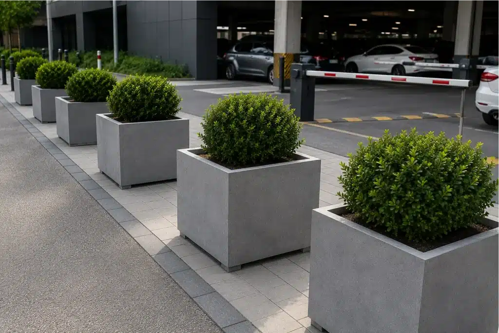 Donice betonowe ustawione jako bariery ochronne przy wjeździe na parking